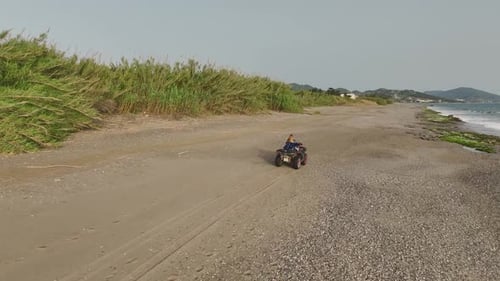 Person Rides ATV on Sandy Ocean Beach