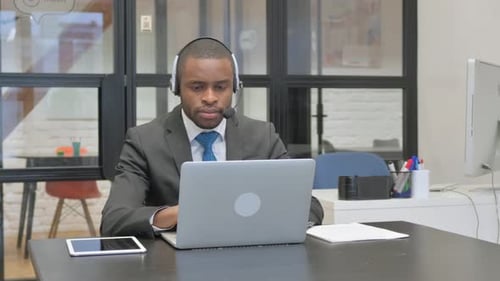 African American Businessman with Headset Working on Laptop in Call Center
