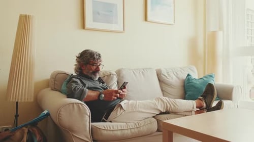 Man Relaxing on Couch Using Phone Indoors