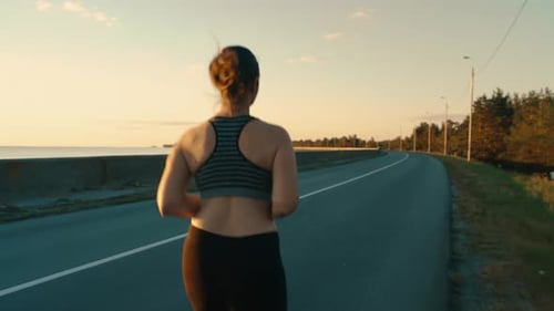 A Girl in a Sports Top Runs Along the Road