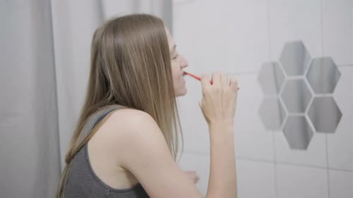 Young Woman Brushing Teeth in Bathroom