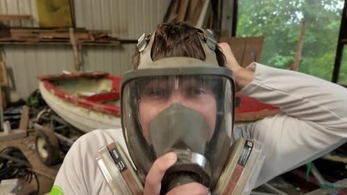 Man Puts On Full Face Respirator Mask in Workshop