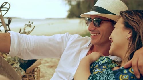 Young Couple Sitting and Looking Out at the Ocean on the Beach