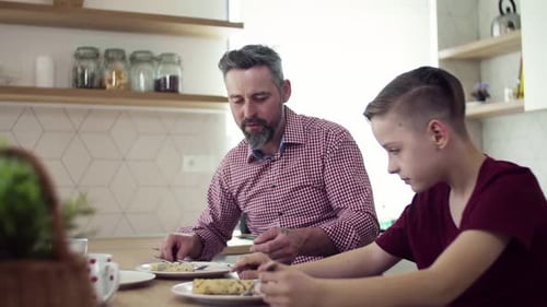 Father and Teen Son Eating Pancakes at Kitchen Table