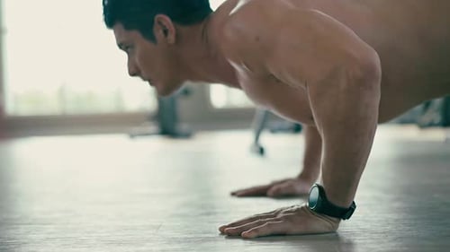 A shirtless muscular man doing push up in a gym. Represents core workout, fitness, and strength