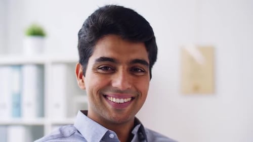 Happy smiling young indian businessman portrait inside office building