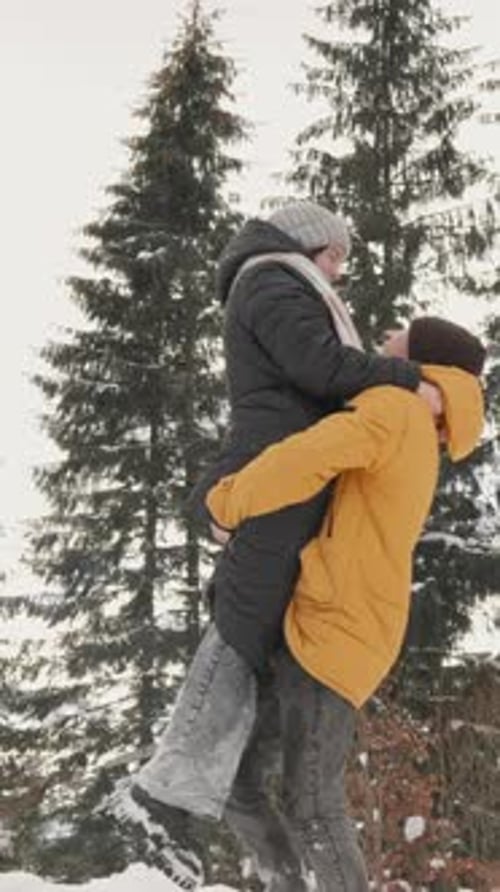 Frohe Winter-Umarmung für ein Paar, das einen herrlichen und verspielten Moment im weichen, flauschigen Schnee teilt