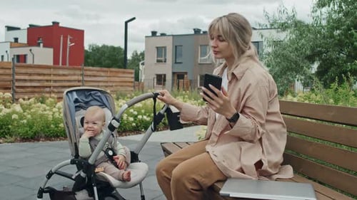 Woman With Baby Texting Message On Smartphone