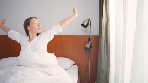 Woman Wakes Up and Stretches in Bed