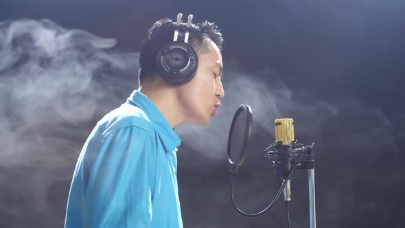 Side View Of Asian Man With Headphone Rapping Into A Condenser ...