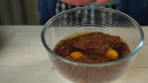 Les mains du chef cassent soigneusement le jaune d'œuf brun dans un bol en verre pour la recette du gâteau