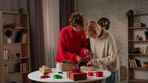 Two Young Women Wrapping Christmas Gifts Together