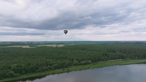 Hot Air Balloons Flying Over the Forest and Lakes at Dusk