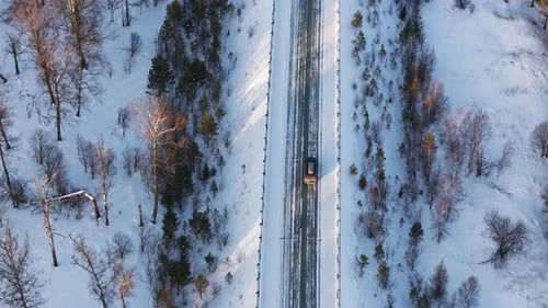 Drone View Capturing Snowcovered Road in Winter Forest Landscape