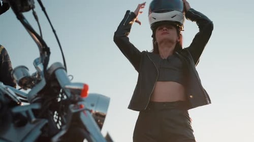Woman Puts on Helmet Beside Motorcycle at Daytime