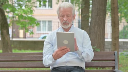 Senior Old Man using Tablet while Sitting in Park