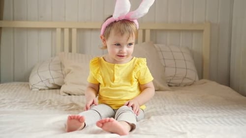 Happy Child Smiles Wearing Bunny Ears on Bed