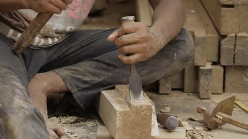Woodworker Chiseling Wood Block with Hammer Tool