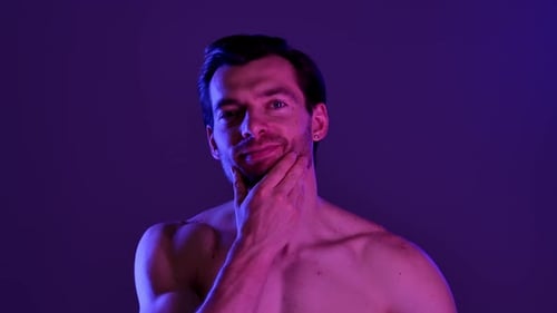 Homme musclé posant dans un éclairage violet avec une serviette