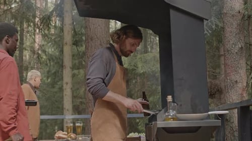 Man Cooking Barbecue Outdoors on Party with Friends in Forest
