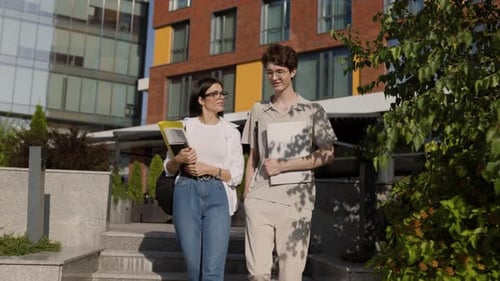 Cheerful Young Man and Woman Students Walking on University Campus Street in Daylight