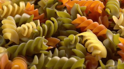 Pâtes italiennes multicolores Fusilli ou Rotini pivotant sous la lumière du soleil en arrière-plan macro. Blé dur