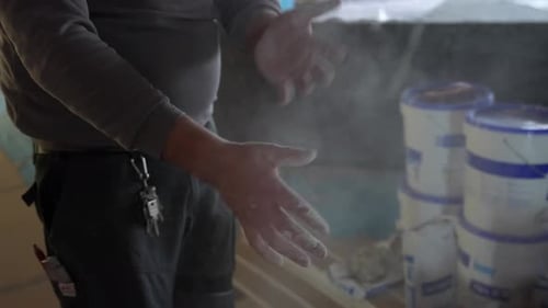 Construction worker clapping dusty dirty cement hands shaking off dust