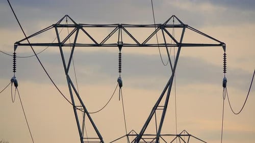 Top part of electrical tower against cloudy yellow sky.