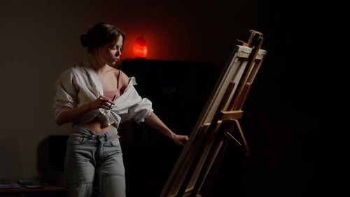 Woman Painting in Dark Room with Easel