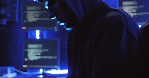 Hooded Coder Using Computer Monitors at Night