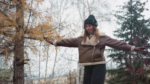 Smiling Girl Balancing on Stone Path with Outstretched Arms in Autumn