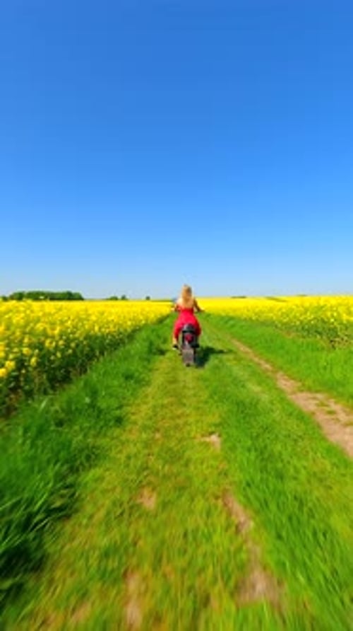 Woman Riding Vintage Motorcycle in the Countryside Through Yellow Fields