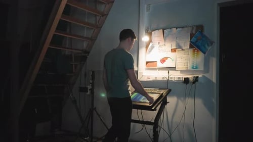 Man Operating Touchscreen Control Panel in Studio Workstation Under Stairs