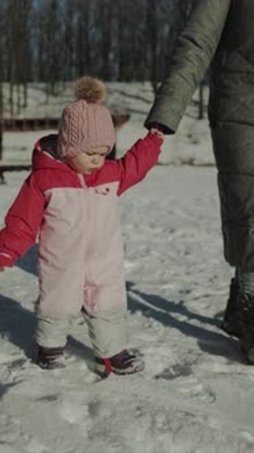 Happy Infant Walks in Winter Snow Holding Hand