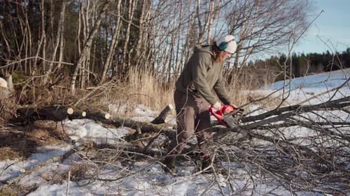 Adult Cuts Fallen Trees with Chainsaw in Winter