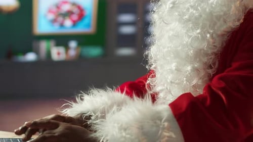 Santa Claus Types on Laptop in Home Setting