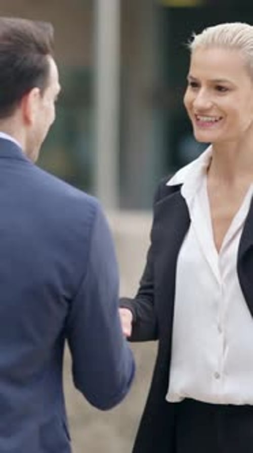 Businesswoman and Businessman Shaking Hands in the City Street