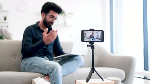 Arabian Man with Laptop Recording Video on Smartphone