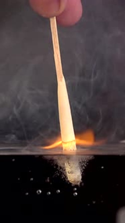 Burning Matchstick Plunged Into Water Creating Bubbles and Smoke