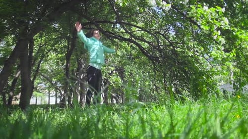 Young woman training. Woman make exercise in the spring park near blooming tree