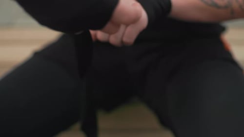 Man Wrapping Hands with Black Boxing Bandages