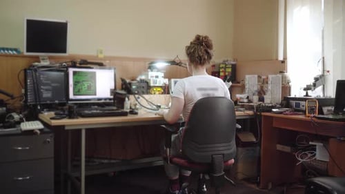 Una trabajadora feliz se gira y sonríe ante una cámara en un taller de servicio de reparación de productos electrónicos Woman Fixes