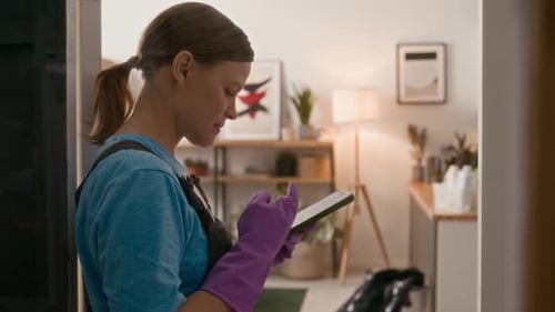 Cleaning Lady Messaging on Smartphone while Man Doing Cleanup at Home Space