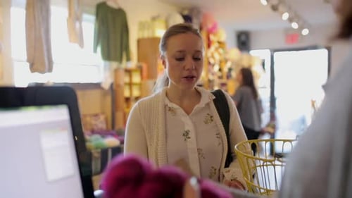 Mature woman buys wool yarn at calgary store with cash register technology