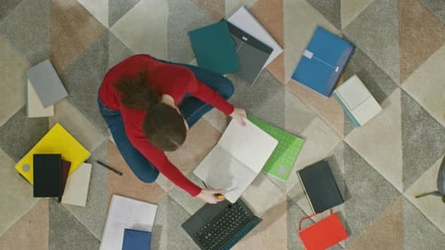 La niña está sentada en el suelo, trabajando o estudiando en una computadora portátil. Escribe en Notebook. Vida acogedora