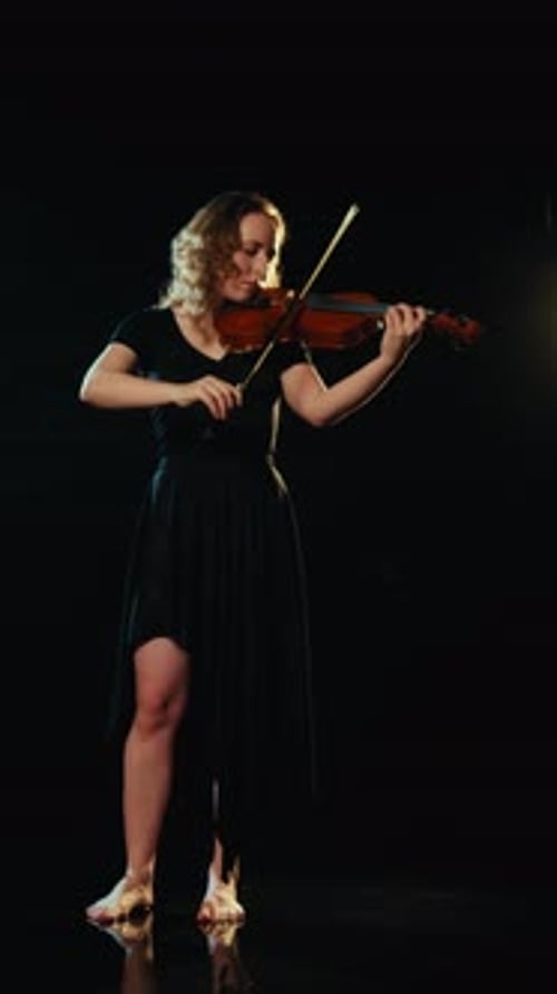 Woman Plays Violin in Dark Setting