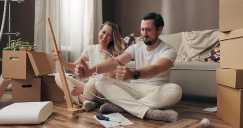 Happy Delighted Husband with Wife Having Fun on Floor in New Modern Light Apertment Moving in