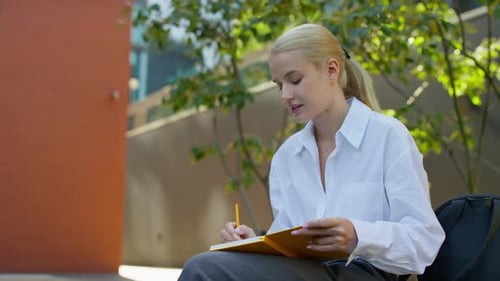 Student Studying Outside with Notebook on Campus