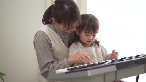 Woman Teaches Child to Play Electronic Piano