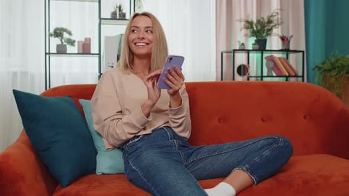 Smiling Woman Using Smartphone on Couch at Home